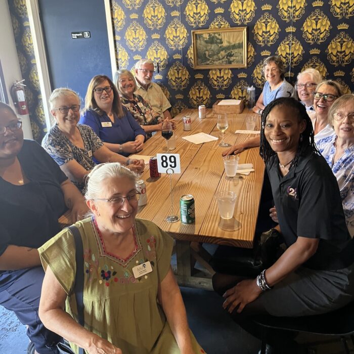 A smiling group of people sits around a wooden table.